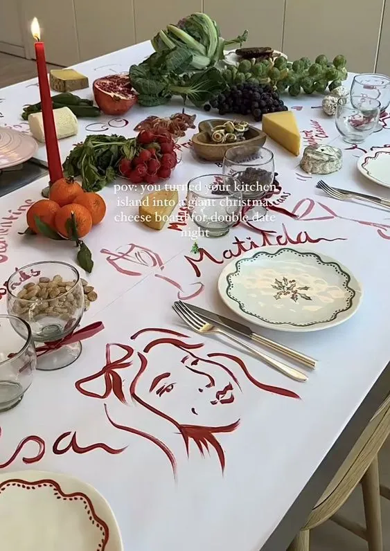 A white table with red flowers and hand-painted drawings on the tablecloth