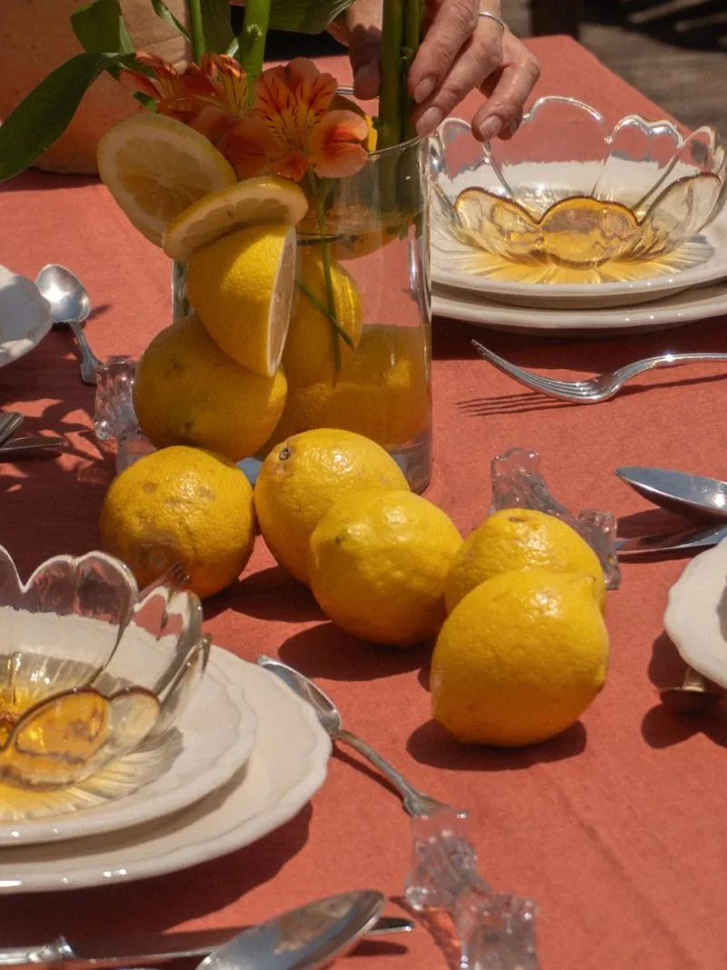 A coral tablecloth set with glass bowls, silver cutlery and lemons